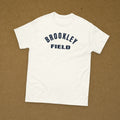 T-shirt blanc imprimé Brookley Field, lettrage seul sans emblème, reproduction WW2, à plat sur fond kraft